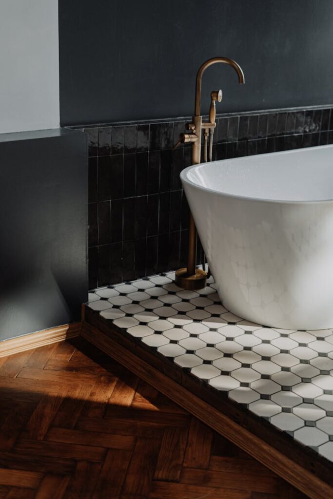 Luxury bathroom featuring a white bathtub with brass fixtures and stylish tiled flooring.
