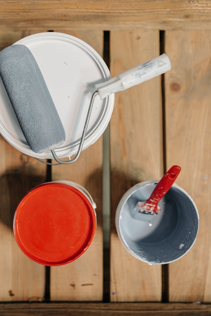 Paint cans and brushes arranged on wooden boards, ready for renovation work.